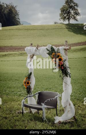 Hochzeitsbogen im Freien mit Sonnenblumen und einer Bank, auf einem Landfeld Stockfoto