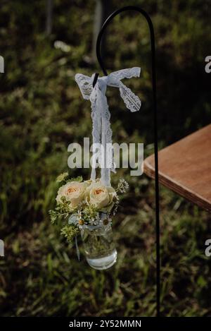 Hochzeitsdekor im Landhausstil mit Rosen, Spitzenband und Kamille in einem Glas Stockfoto