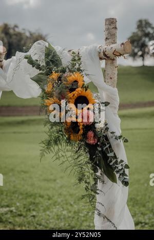 Hochzeitsbogen im Freien mit Sonnenblumen auf einem Landfeld. Stockfoto