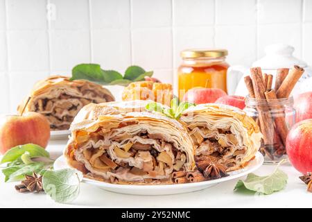 Hausgemachter herbstlicher Apfelstrudel mit karamelisierten Äpfeln, Rosinen, Nüssen, Honig, Zimtgewürzen, auf Teller auf Küchentisch Kopierraum Stockfoto