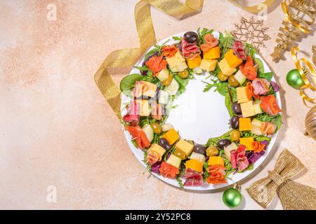 Weihnachtsessen, trendige Vorspeisen. Wurstkranz aus Wurst, Fleisch, Käse, Oliven, Gemüse auf beigefarbenem Tischhintergrund mit g Stockfoto