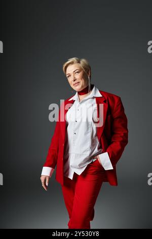 Eine elegante Erwachsene Frau steht selbstbewusst in einem markanten roten Ensemble und zeigt ihren einzigartigen Stil. Stockfoto