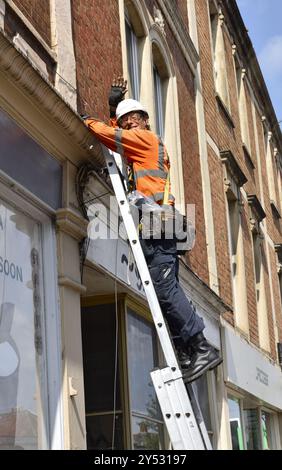 Telefontechniker oben auf der Leiter, der neue Lichtwellenleiter installiert Stockfoto