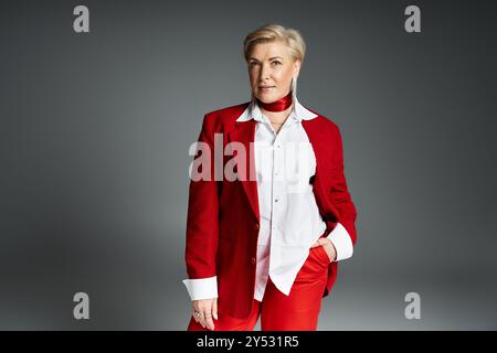 Eine modische Frau strahlt Selbstvertrauen in raffinierte rote und weiße Kleidung aus, die im Stehen steht. Stockfoto