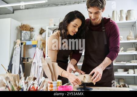 Ein Paar formt fröhlich Ton, während es Töpferei in seinem kreativen Raum herstellt. Stockfoto