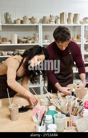 Ein Paar bastelt fröhlich Töpferwaren in einem modernen Studio. Stockfoto