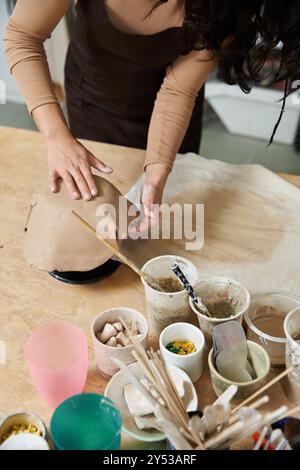 Junge Frau auf Schürze, die Töpferei in gut beleuchtetem Atelier macht. Stockfoto