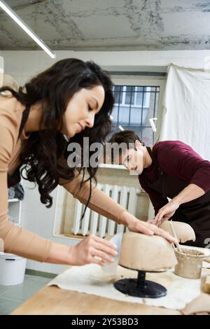 Ein Paar formt in ihrem künstlerischen Raum fröhlich Ton in Töpferei. Stockfoto