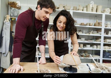 Ein Paar formt fröhlich Ton, während es in einem Töpferstudio arbeitet. Stockfoto