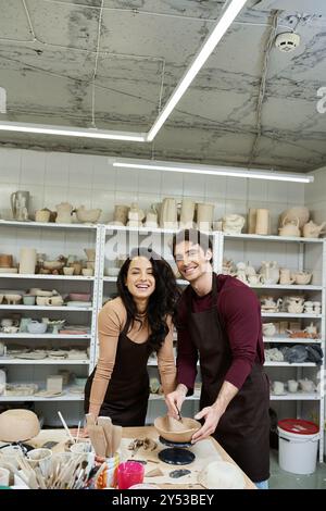 Ein Paar formt in einem modernen Töpferstudio fröhlich Ton. Stockfoto