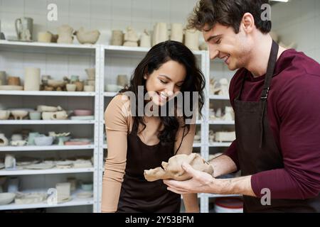 Ein Paar formt fröhlich Ton und teilt Lachen und Kreativität in ihrem Studio. Stockfoto