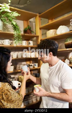 Ein Paar bastelt fröhlich Töpferwaren und teilt Kreativität in einem modernen Ambiente. Stockfoto
