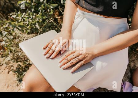 Eine Frau sitzt auf dem Boden mit offenem Laptop vor sich Stockfoto