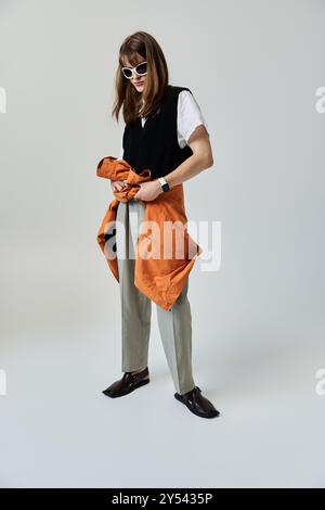 Ein modischer junger Mann posiert selbstbewusst in stilvoller Kleidung und bereitet sich auf ein fesselndes Fotoshooting vor. Stockfoto