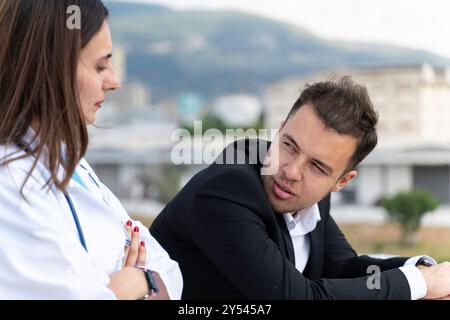Ein Mann und eine Frau stehen auf einem Balkon, der Mann trägt einen Anzug und die Frau trägt einen weißen Mantel. Sie sehen sich etwas in der DISS an Stockfoto