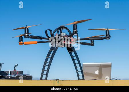 Eine große Drohne mit sechs Propellern sitzt auf einer Leiter. Die Drohne ist schwarz und orange Stockfoto