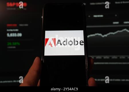 In dieser Fotoabbildung wird das Logo von Adobe Inc. Auf einem Smartphone mit Hintergrund einer S&P-Index-Website angezeigt. Stockfoto