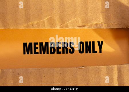 Nur für Mitglieder geschriebene Nachricht auf zerrissenem Papppapier mit orangem Hintergrund. Symbol nur konzeptionelle Elemente. Kopierbereich. Stockfoto