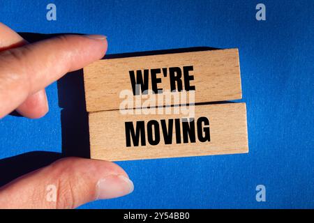 Wir bewegen eine Botschaft auf Holzblöcken mit blauem Hintergrund. Begriffliches Symbol, dass wir uns bewegen. Kopierbereich. Stockfoto