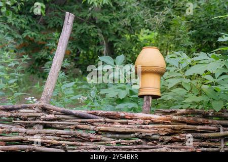 Vintage-Topf auf einem Weidenzaun im Dorf. Ethnische Kunst. Stockfoto