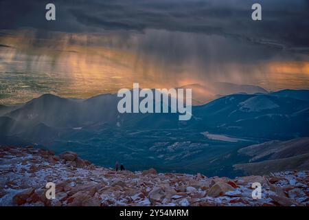 Am Pikes Peak Gipfel im Pike National Forest in der Nähe von Colorado Springs, Colorado, bricht die Sonne durch einen Schneesturm im Sommer. Stockfoto