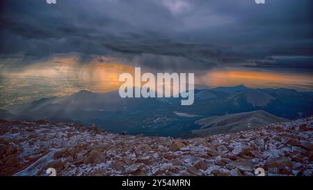 Am Pikes Peak Gipfel im Pike National Forest in der Nähe von Colorado Springs, Colorado, bricht die Sonne durch einen Schneesturm im Sommer. Stockfoto