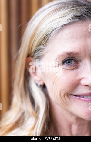 Zu Hause, lächelnde Seniorin mit blonden Haaren und Ohrringen, Nahaufnahme Porträt Stockfoto