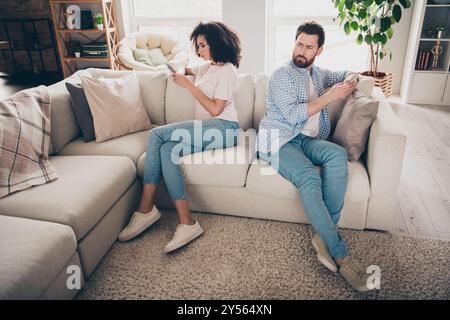 Foto von zwei Leuten Mädchen sitzen Couch benutzt Handy-Smartphone Verdächtige, die drinnen betrügen Stockfoto