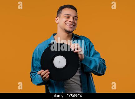 Stilvoller Mann mit Schallplatte auf Gelb. Hobby, Musikliebhaber, Sammlung Stockfoto