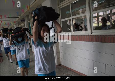 Schüler der Junior High School legten ihre Schultaschen auf den Kopf und gingen nach draußen, um an der jährlichen Erdbebenbohrung in Taipeh im September teilzunehmen Stockfoto
