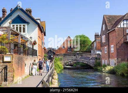 Menschen, die am Fluss Itchen spazieren gehen, und der Bischof on the Bridge Pub mit der City Mill, Einer restaurierten Wassermühle aus dem 18. Jahrhundert in Winchester Hampshire, Großbritannien Stockfoto