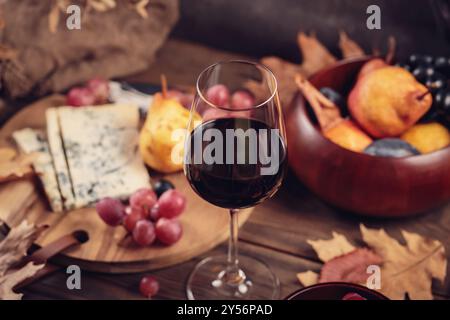 Herbstpicknick mit Wein- und Käseplatte, Früchten und trockenen Blättern Stockfoto