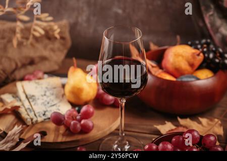 Herbstpicknick mit Wein- und Käseplatte, Früchten und trockenen Blättern Stockfoto