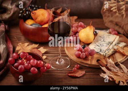 Herbstpicknick mit Wein- und Käseplatte, Früchten und trockenen Blättern Stockfoto