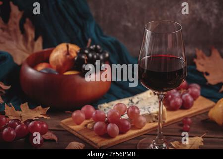 Herbstpicknick mit Wein- und Käseplatte, Früchten und trockenen Blättern Stockfoto