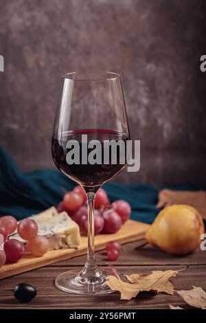 Herbstpicknick mit Wein- und Käseplatte, Früchten und trockenen Blättern Stockfoto