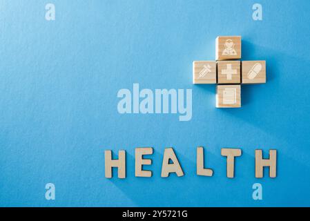 Gesundheit Hintergrund gebildet mit Holzblöcken Siebdruck mit medizinischen Symbolen und Buchstaben, die das Wort Gesundheit auf einem blauen Hintergrund bilden. Draufsicht. Stockfoto