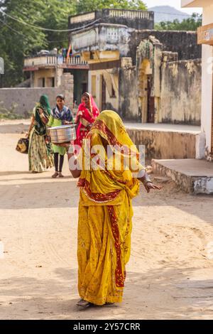 Devnagar, Ajmer, Rajasthan, Indien. November 2022. Frau in Gelb, die eine Straße in Rajasthan entlang geht. Stockfoto