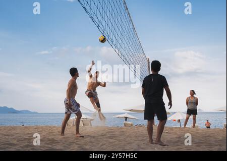 Teams mit multinationalen Spielern spielen im Sommer Beachvolleyball am Meer in Nha Trang in Asien. Nha Trang, Vietnam - 4. August 2024 Stockfoto