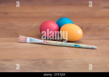 Gruppe von farbigen ostereiern zusammen mit einem einzelnen Pinsel. Handgefertigtes osterei in Pastellfarben für den Osten im april. Dekorative Feiertage präsentieren Handwerkskunst Stockfoto