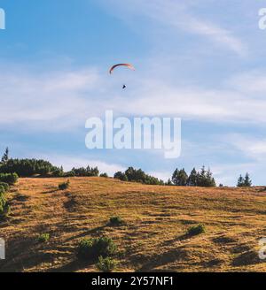 Ein Gleitschirmflieger, der durch den klaren blauen Himmel in Bayern schwebt. Stockfoto