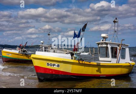 Sopot, Polen - 31. August 2024: Gelbe Fischerboote am Strand, raue Ostsee, bewölkter Himmel. Stockfoto