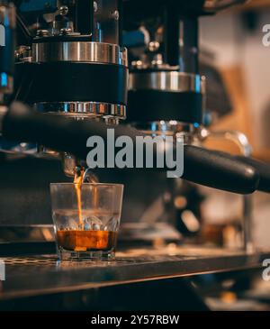 Espresso, der aus einem Portafilter in einer Kaffeemaschine in ein Glas gegossen wird. Stockfoto