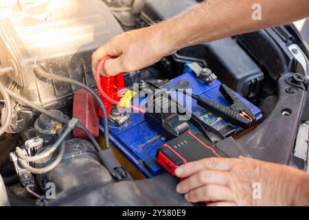 Der Fahrer lädt die entladene Batterie des Fahrzeugs mit einem Starthilfegerät auf. Batterie entladen. Stockfoto