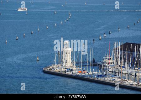 Venedig, Venetien, Italien. 16. September 2024: Yachten und Boote vertäuten in einem Jachthafen in Venedig, Italien, mit einem Leuchtturm im Hintergrund. Stockfoto