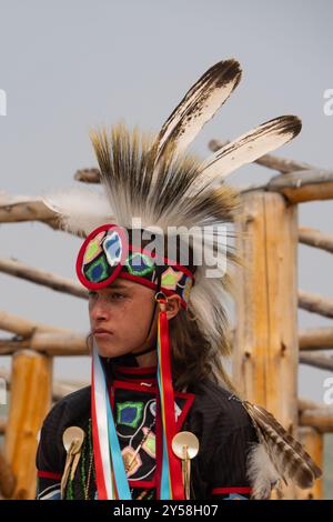 Nahaufnahme eines jungen Indianers in einem gefiederten Kopfschmuck und voller Powwow-Insignien. Fotografiert in Lodge Pole, Montana. Stockfoto