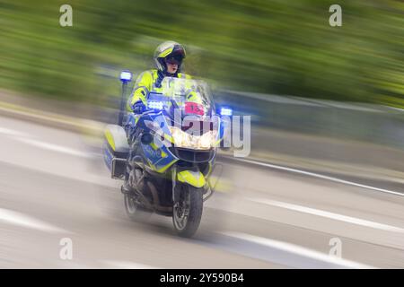 Polizist fährt mit hoher Geschwindigkeit auf einem Motorrad auf einer Straße mit blinkenden blauen Lichtern, Stuttgart, Baden-Württemberg, Deutschland, Europa Stockfoto