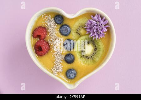 Peach smoothie Schüssel mit Blaubeeren, Kiwi, weiße Chia Samen und Himbeeren in Herzform Schüssel Stockfoto