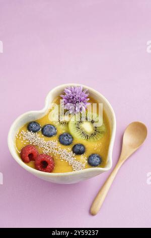 Peach smoothie Schüssel mit Blaubeeren, Kiwi, weiße Chia Samen und Himbeeren in Herzform Schüssel Stockfoto