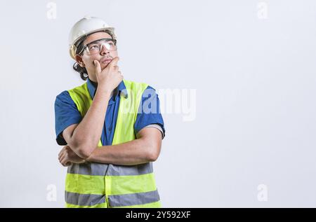 Nachdenklicher Baumeister-Mann mit Hand am Kinn isoliert. Der junge Baumeister fragt sich, wie er mit Hand am Kinn aufblickt Stockfoto